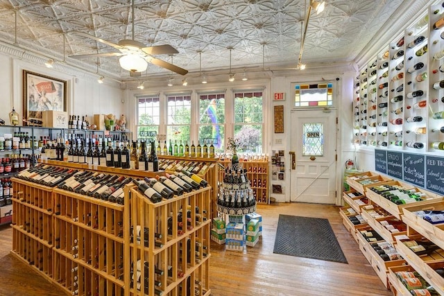 wine area with hardwood / wood-style flooring, crown molding, and ceiling fan
