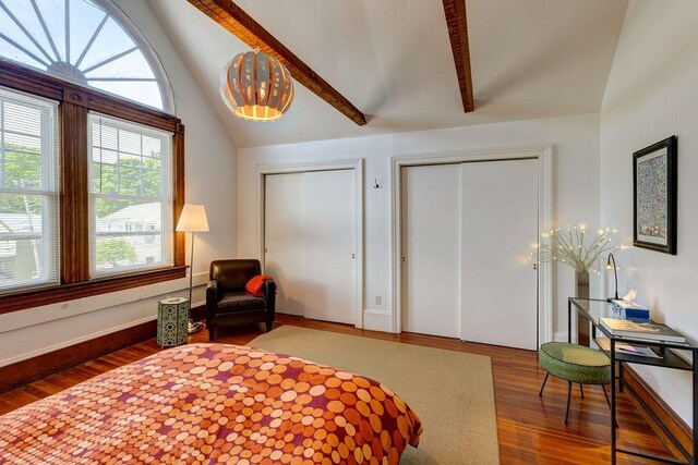 bedroom featuring two closets, wood-type flooring, and lofted ceiling with beams