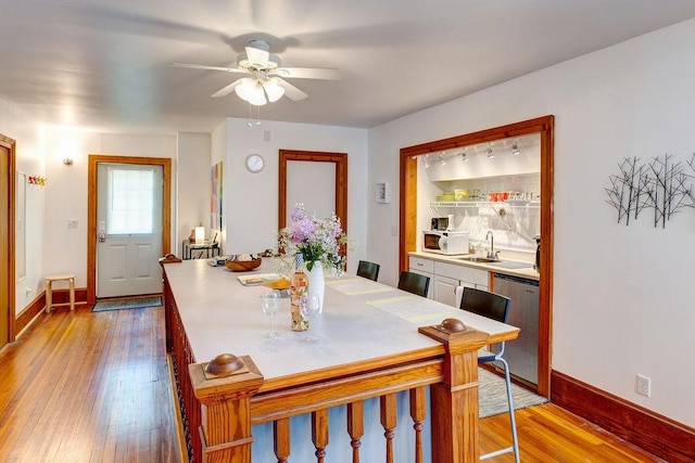 dining space with sink, light hardwood / wood-style floors, and ceiling fan