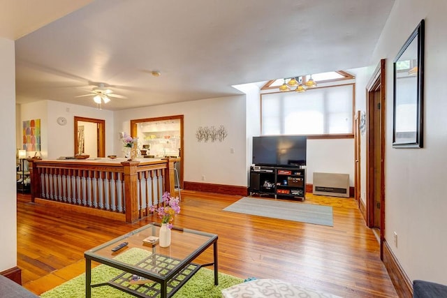 living room featuring ceiling fan with notable chandelier and light wood-type flooring