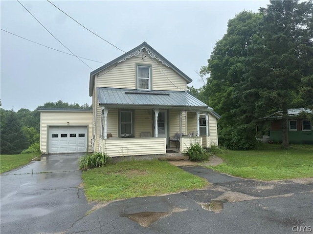 view of front of home with a garage, covered porch, and a front yard