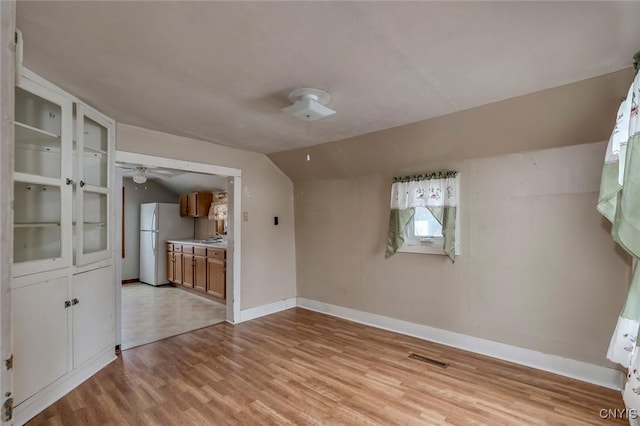 empty room with lofted ceiling, light hardwood / wood-style floors, and ceiling fan