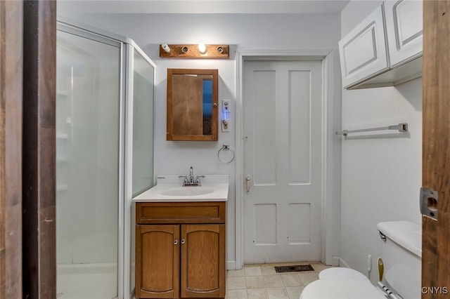 bathroom with vanity, toilet, a shower with shower door, and tile patterned flooring