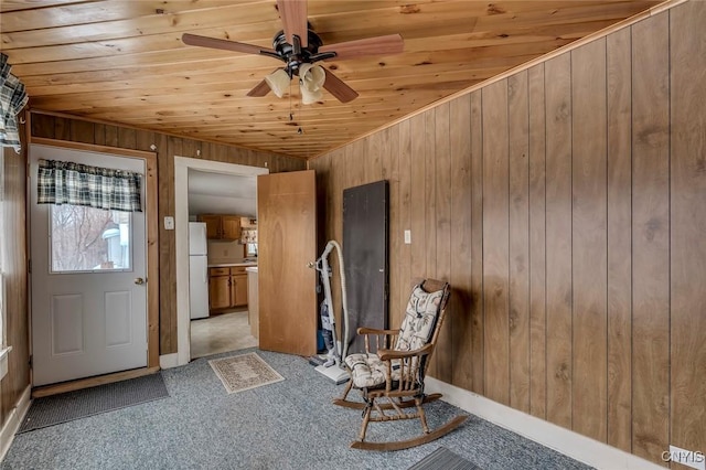 unfurnished room with ceiling fan, wooden walls, light carpet, and wooden ceiling