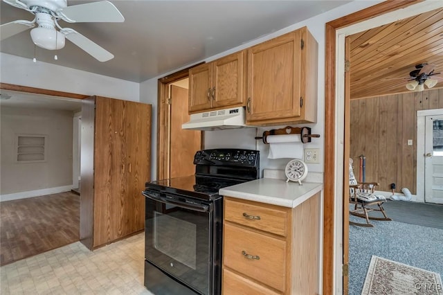 kitchen with ceiling fan, wooden walls, and electric range