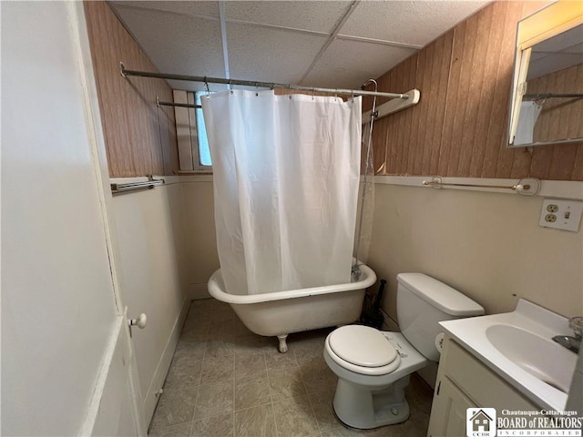 full bathroom featuring a drop ceiling, vanity, wooden walls, separate shower and tub, and toilet