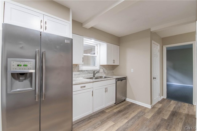 kitchen featuring beam ceiling, white cabinetry, sink, tasteful backsplash, and appliances with stainless steel finishes