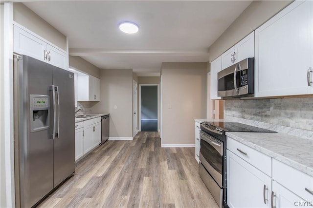 kitchen featuring white cabinets, light stone countertops, and stainless steel appliances