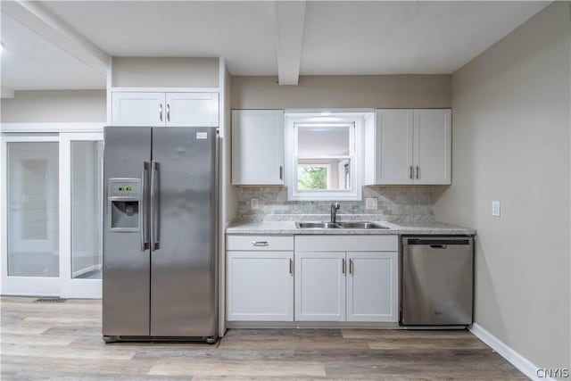 kitchen with sink, decorative backsplash, beamed ceiling, white cabinetry, and stainless steel appliances