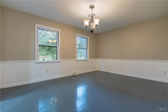 empty room with a chandelier and dark hardwood / wood-style flooring