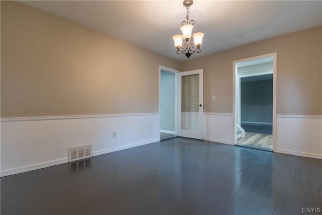 empty room featuring dark hardwood / wood-style floors and a notable chandelier