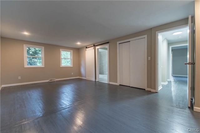 unfurnished room featuring a barn door and dark wood-type flooring