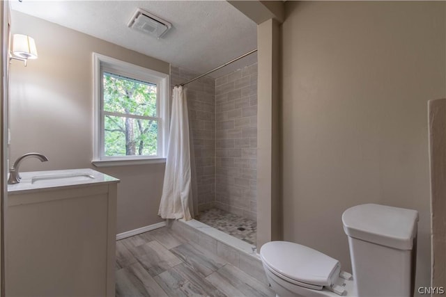 bathroom featuring walk in shower, a textured ceiling, vanity, hardwood / wood-style floors, and toilet