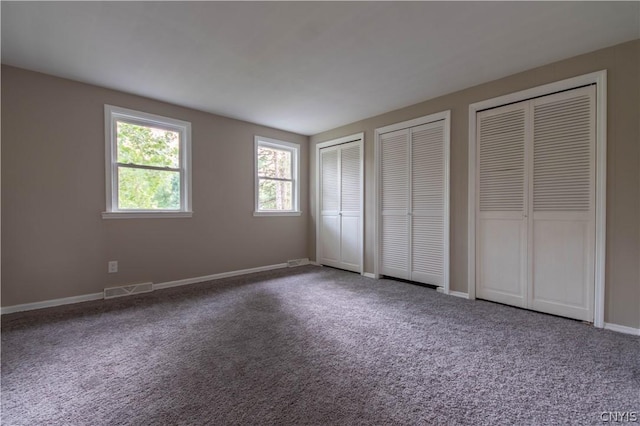 unfurnished bedroom with carpet and two closets