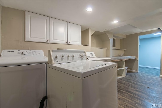 clothes washing area with cabinets, washer and dryer, and hardwood / wood-style flooring