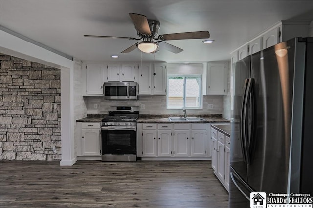 kitchen with sink, dark hardwood / wood-style floors, decorative backsplash, white cabinetry, and stainless steel appliances