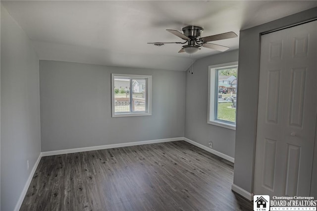 empty room featuring ceiling fan, hardwood / wood-style floors, a healthy amount of sunlight, and vaulted ceiling