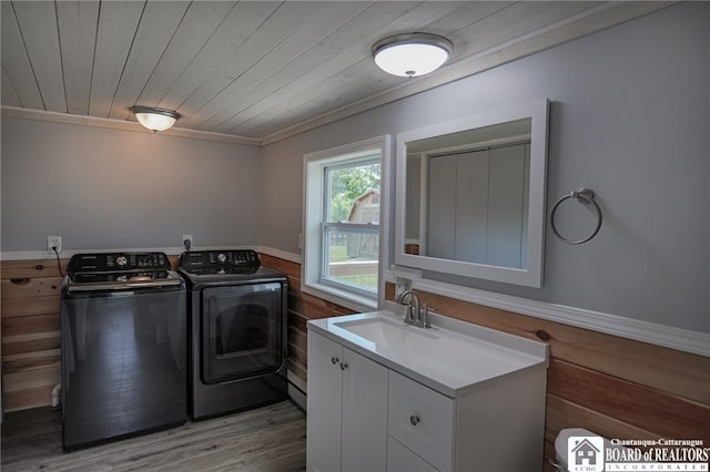 washroom featuring crown molding, sink, washing machine and dryer, light hardwood / wood-style floors, and wood ceiling