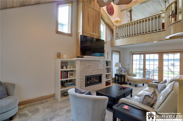 carpeted living room featuring a tile fireplace, ceiling fan, plenty of natural light, and french doors