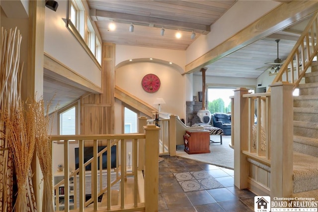 interior space with ceiling fan, dark carpet, beamed ceiling, track lighting, and wood ceiling