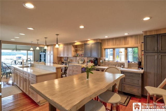 kitchen featuring a center island with sink, hanging light fixtures, sink, and a wealth of natural light