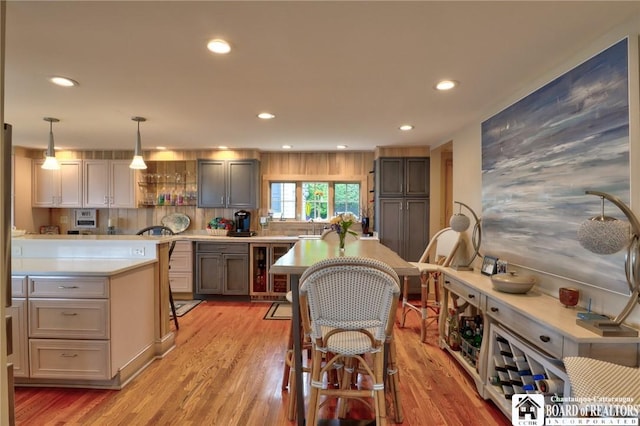 kitchen with pendant lighting, decorative backsplash, gray cabinetry, and light hardwood / wood-style flooring