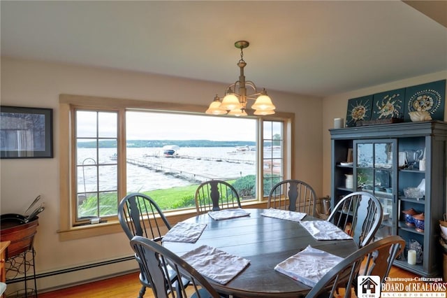 dining room with a notable chandelier, light hardwood / wood-style floors, a water view, and a baseboard heating unit