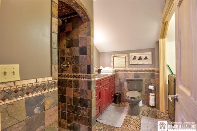 bathroom with vanity, vaulted ceiling, a shower, tile walls, and toilet