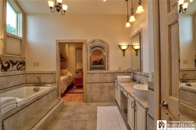 bathroom featuring vanity, tile patterned flooring, a relaxing tiled tub, tile walls, and a notable chandelier