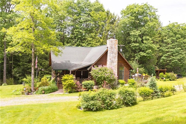 view of side of home featuring log exterior, a lawn, a chimney, and driveway