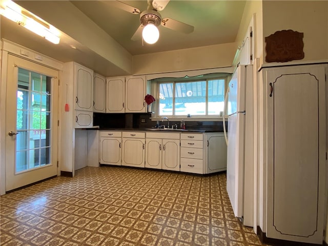 kitchen featuring ceiling fan, white refrigerator, sink, and light tile floors