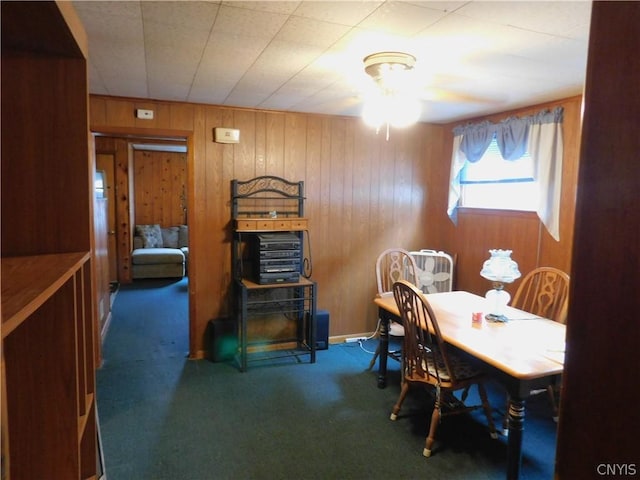 carpeted dining area featuring wooden walls