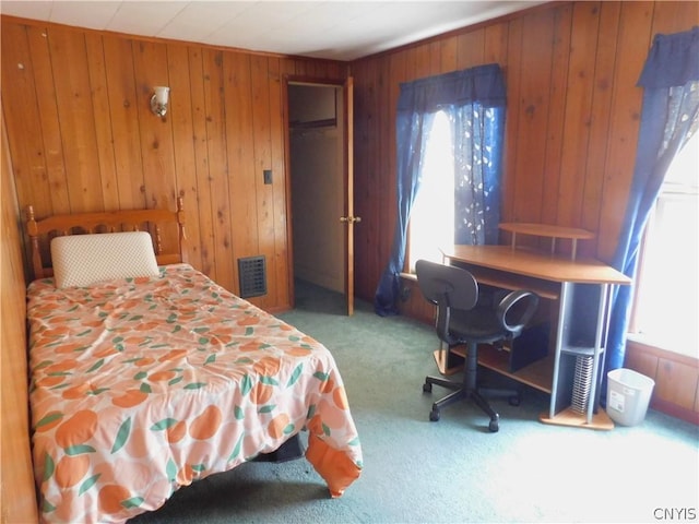 carpeted bedroom with multiple windows, visible vents, and wooden walls