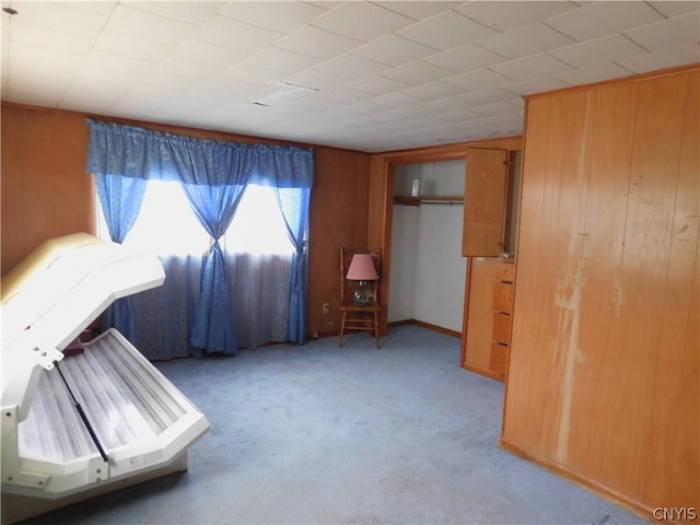 unfurnished bedroom featuring wooden walls and light colored carpet