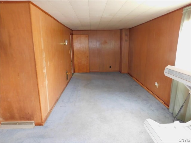 unfurnished room with light colored carpet, wood walls, and visible vents