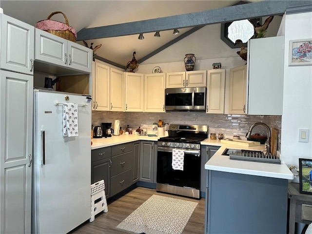 kitchen with gray cabinetry, lofted ceiling with beams, sink, appliances with stainless steel finishes, and tasteful backsplash