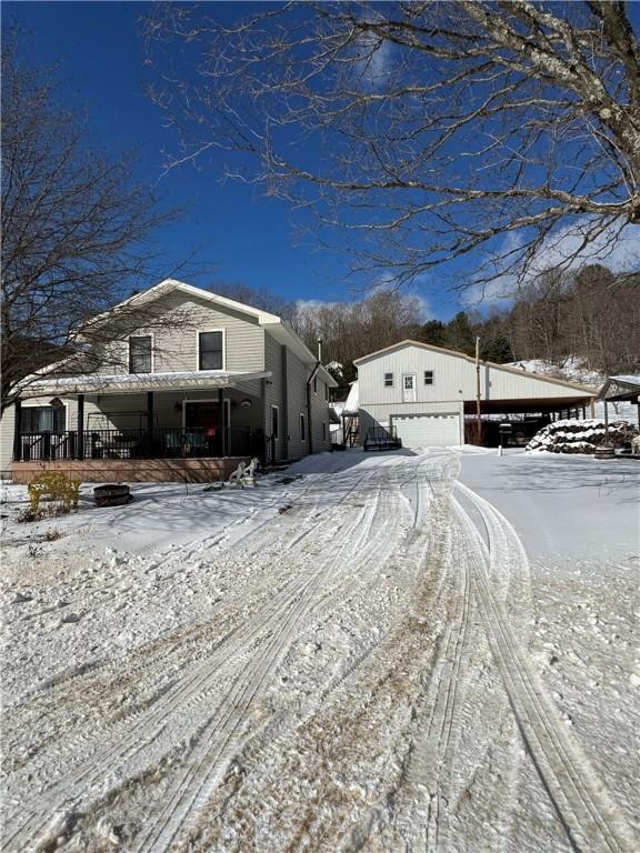 snow covered property featuring a porch and an outbuilding