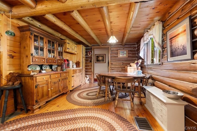 dining area featuring log walls, wooden ceiling, beamed ceiling, and light wood-type flooring