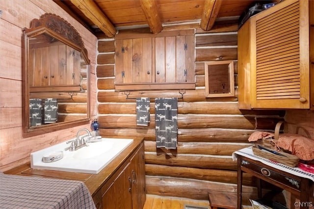 bathroom with vanity, wooden ceiling, rustic walls, and beam ceiling