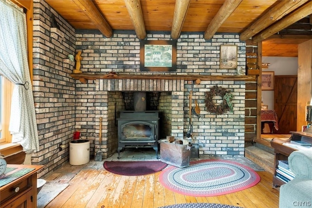 unfurnished living room with wood ceiling, a wood stove, beamed ceiling, and brick wall