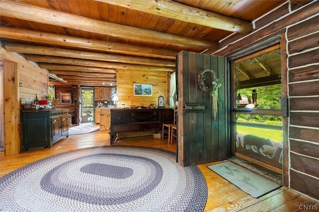 interior space featuring light hardwood / wood-style flooring, beam ceiling, log walls, wooden ceiling, and wood walls