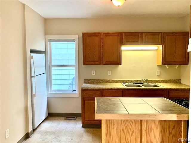 2739 State Route 48, Minetto, NY 13115 - kitchen with freestanding refrigerator, tile counters, brown cabinetry, and plenty of natural light