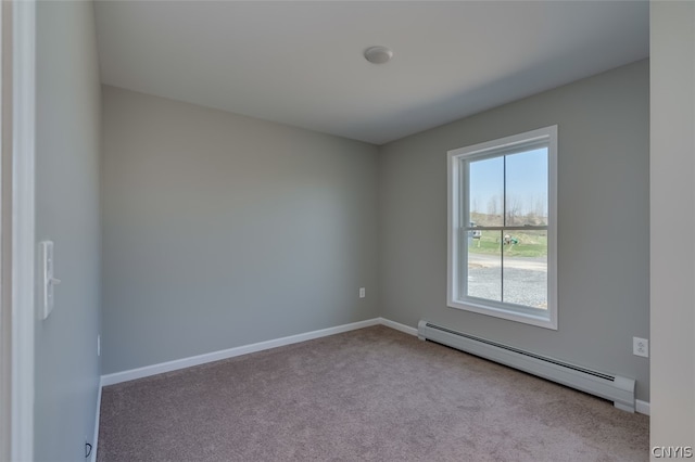 spare room featuring a baseboard heating unit and carpet