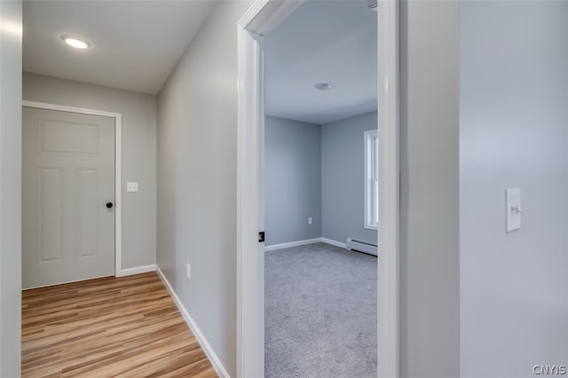 hallway featuring light carpet and a baseboard heating unit