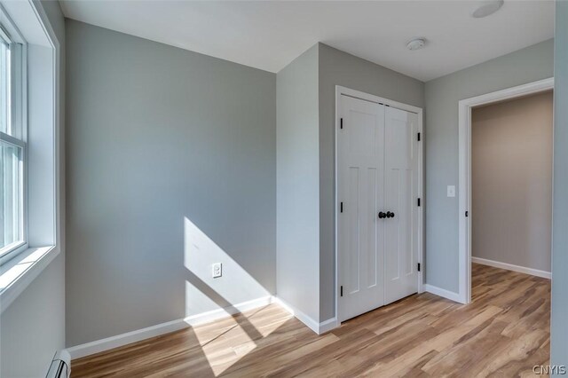 22218 Freedom Dr, Champion, NY 13619 - unfurnished bedroom featuring a baseboard radiator, baseboards, a closet, and light wood-style flooring