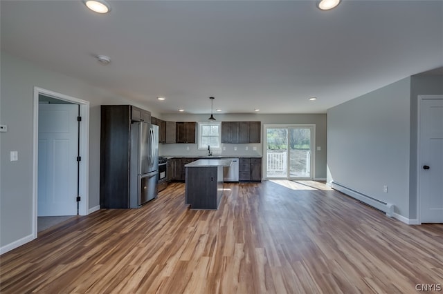 kitchen featuring a center island, baseboard heating, appliances with stainless steel finishes, and hardwood / wood-style floors