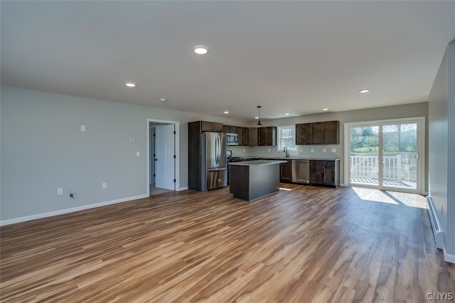 unfurnished living room featuring sink, a baseboard radiator, and hardwood / wood-style flooring