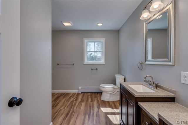 bathroom featuring hardwood / wood-style flooring, baseboard heating, toilet, and vanity