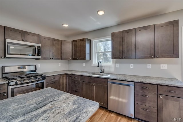 22218 Freedom Dr, Champion, NY 13619 - kitchen featuring dark brown cabinets, a sink, light wood-style floors, appliances with stainless steel finishes, and recessed lighting