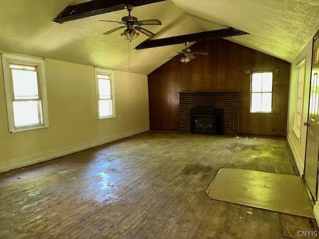 unfurnished living room with a fireplace, hardwood / wood-style floors, lofted ceiling with beams, and wooden walls